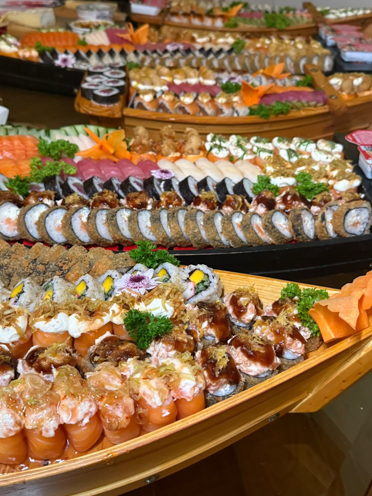 Buffet com várias barcas de sushi enfileiradas